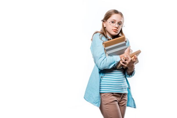 χαριτωμένο εφηβικό κορίτσι σε γυαλιά κρατώντας στοίβα από βιβλία και βλέπουν τα φωτογραφικών μηχανών που απομονώνονται σε λευκό - Φωτογραφία, εικόνα