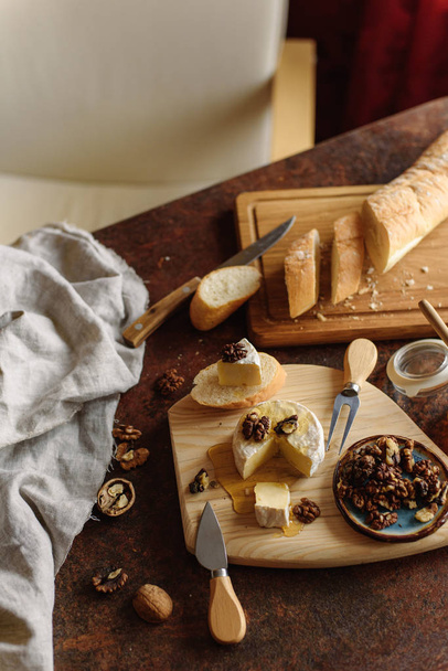 Blick auf leckeres Essen mit Brie, Walnüssen und Baguette in Scheiben. - Foto, Bild