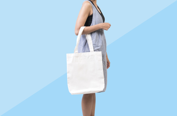 Chica está sosteniendo tela de lona bolsa para maqueta plantilla en blanco
  - Foto, imagen