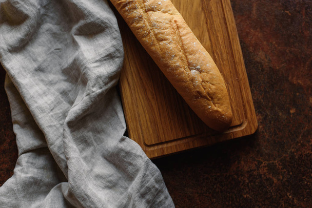 Top view of  baguette served on wooden chopping board with napkin - 写真・画像