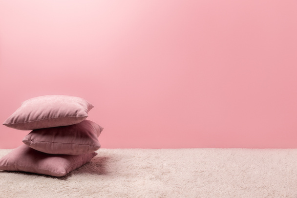 pila de almohadas en la alfombra delante de la pared rosa
 - Foto, Imagen