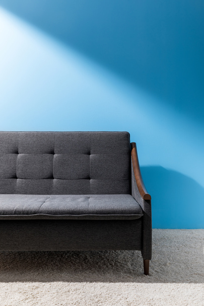 sofá cinza acolhedor na frente da parede azul
 - Foto, Imagem