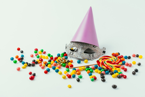 vista de cerca de máscara de mascarada, cono de fiesta y dulces aislados en gris
   - Foto, imagen