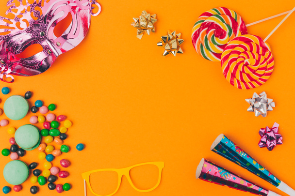 plano con caramelos y objetos de fiesta aislados en naranja, concepto de vacaciones purim
 - Foto, Imagen