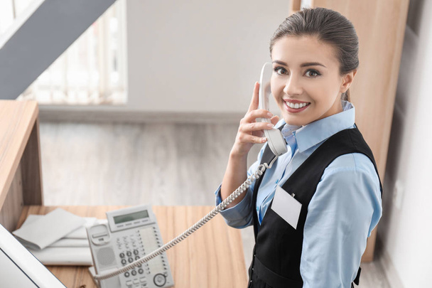 Female receptionist talking on phone in hotel - Фото, изображение