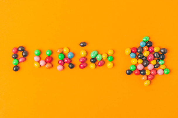 vista superior de letras de purim hechas de caramelos y estrella aislada en naranja
 - Foto, imagen