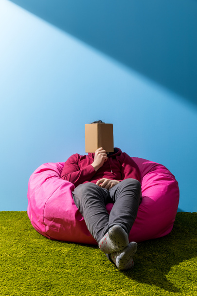 man reading book in bean bag in front of blue wall - Foto, Bild