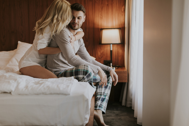Любящая и обнимающая пара на кровати в комнате - Фото, изображение