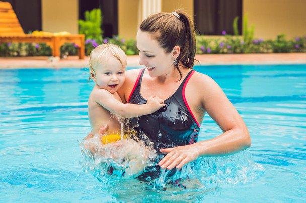 若い母親が彼女の幼い息子を教えるスイミング プールで泳ぐ方法. - 写真・画像
