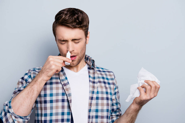 Portrait of attractive guy with a nasal spray and tissue in hand - Fotografie, Obrázek