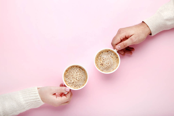 Female and male hand holding cups of coffee on pink background - Zdjęcie, obraz