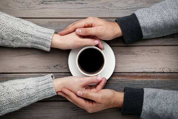 Female and male hand holding each other with cup of coffee - Fotoğraf, Görsel