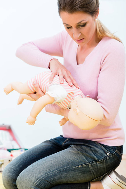 Woman practicing revival of infant on baby doll in first aid course  - Photo, Image