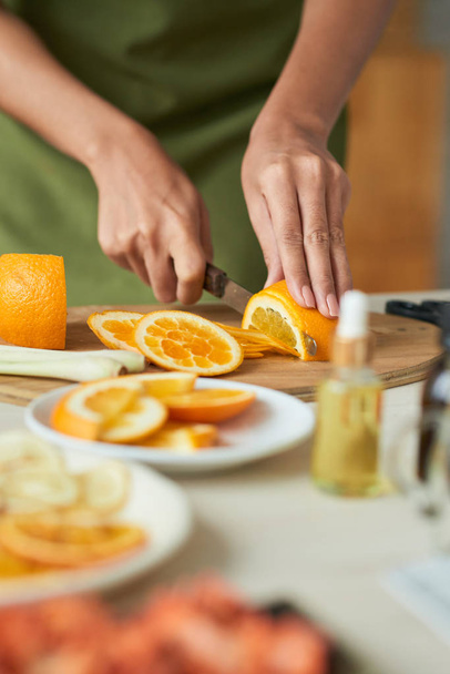Ręce kobiety krojenie dojrzałych pomarańczy na deska do krojenia - Zdjęcie, obraz
