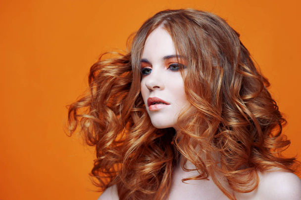 Beautiful redheaded girl with luxurious curly hair. Studio portrait on yellow background. Excellent hair - Foto, Bild