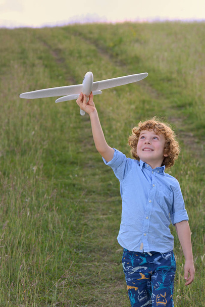 little boy holding a wooden airplane model - Foto, afbeelding