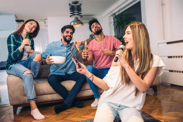 Ystävät pelaavat karaokea kotona. Käsitys ystävyydestä, kodin viihteestä ja ihmisistä - Valokuva, kuva