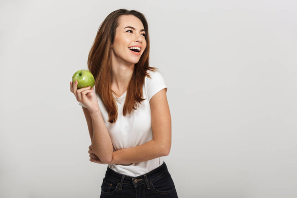 Portrait of a cheerful young woman holding green apple - Valokuva, kuva