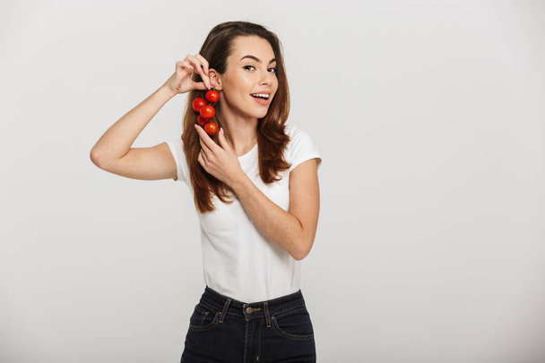 Portrait of a pretty young woman holding cherry tomatoes - Fotó, kép