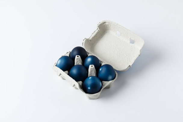 six œufs de Pâques peints en bleu dans un bac à œufs sur fond blanc
 - Photo, image