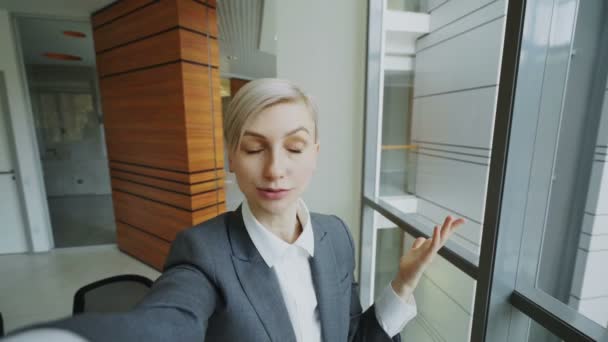 POV of young businesswoman in suit having online video chat using smartphone camera and talking to his colleagues in modern office - Séquence, vidéo
