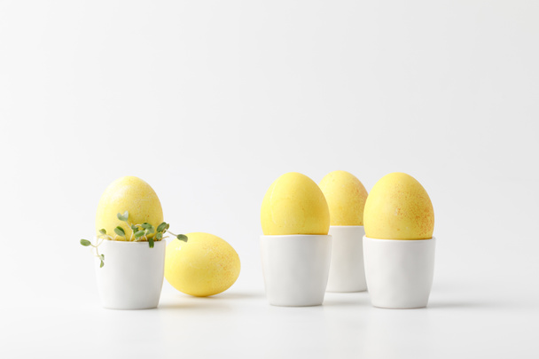 żółty malowane pisanki w jajku stoi na biały - Zdjęcie, obraz