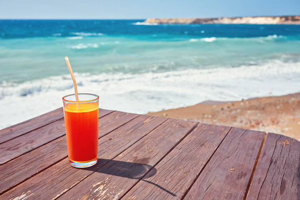 Melon juice on a sea beach. Glasses with red drink and straw stands on a fallen coconut. - Fotoğraf, Görsel