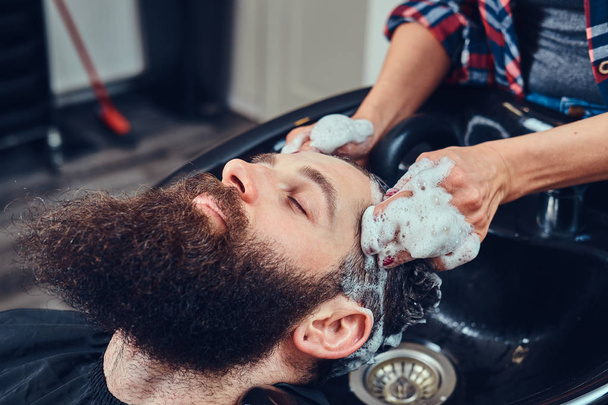 Coiffeur professionnel lavant les cheveux du client dans un salon de coiffure
. - Photo, image