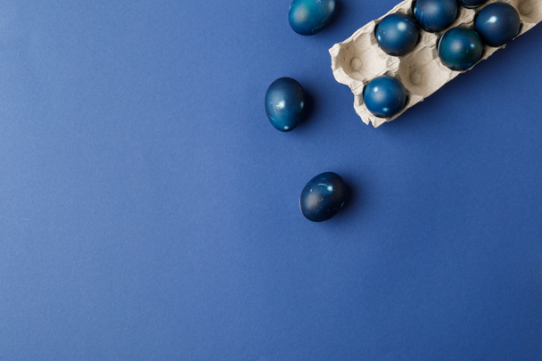 青い表面上の青い塗られたイースターエッグと卵トレイ トップ表示 - 写真・画像