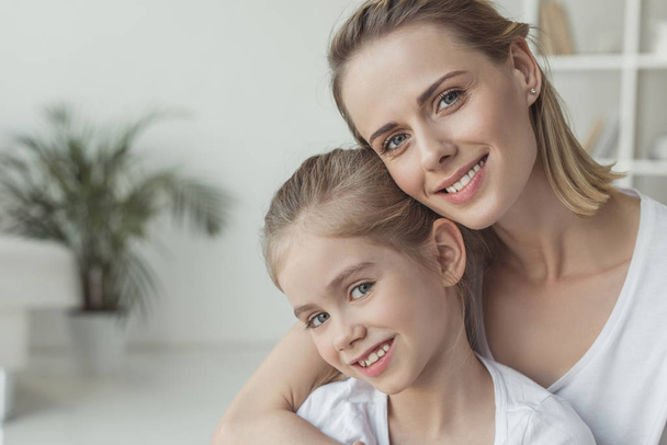 close-up portrait of mother and daughter embracing at home - Photo, Image