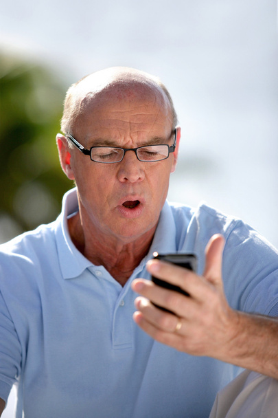 Man staring at his mobile phone is disbelief - Foto, Bild