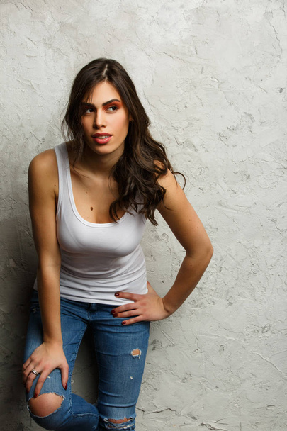 Picture of beautiful brunette in white tank top and ripped jeans - Foto, Imagen