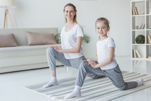 счастливая мать и дочь разогреваются перед тренировкой на ковриках для йоги
 - Фото, изображение