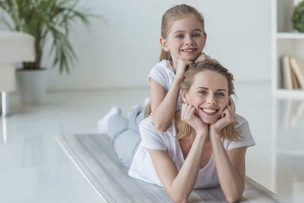 happy mother and daughter lying on floor together - Фото, зображення