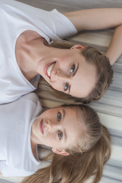 top view of mother and daughter looking at camera while relaxing - Foto, imagen