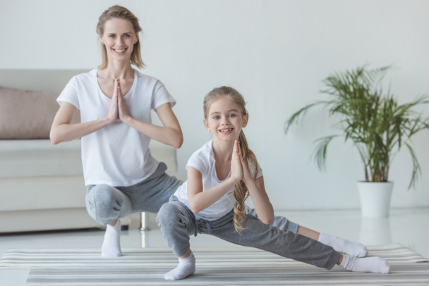 mother and daughter practicing yoga together at home - 写真・画像