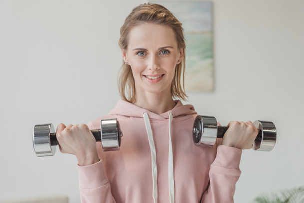 beautiful adult woman working out with dumbbells at home - Φωτογραφία, εικόνα