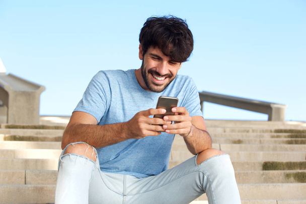 Portrait de jeune homme heureux assis avec téléphone portable
 - Photo, image