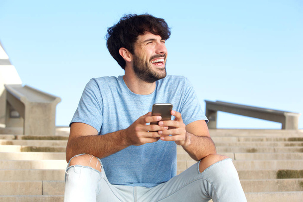 Portrait de beau jeune homme riant avec téléphone portable
 - Photo, image