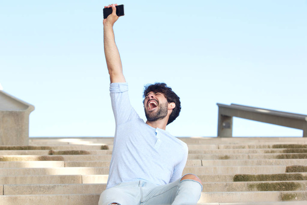 Retrato de un joven golpeando el aire con un teléfono móvil
 - Foto, Imagen