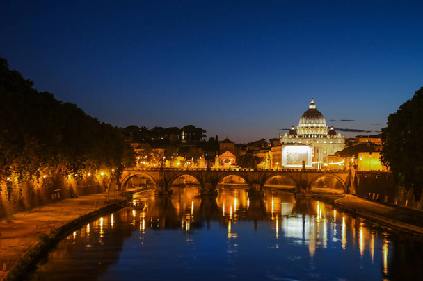 Vista noturna da Basílica de St. Peters. Ponte Sant Angelo e Rio Tibre em Roma - Itália. Pôr-do-sol dramático com reflexo de água bonito. Itália cartão postal
 - Foto, Imagem