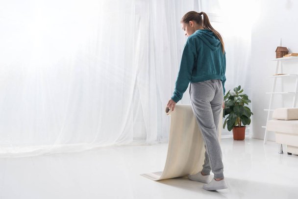 junge Frau legt Yogamatte zu Hause auf den Boden - Foto, Bild