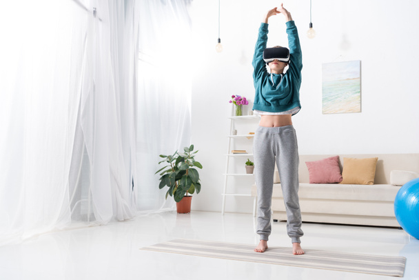girl doing yoga with virtual reality headset on yoga mat at home - Фото, изображение