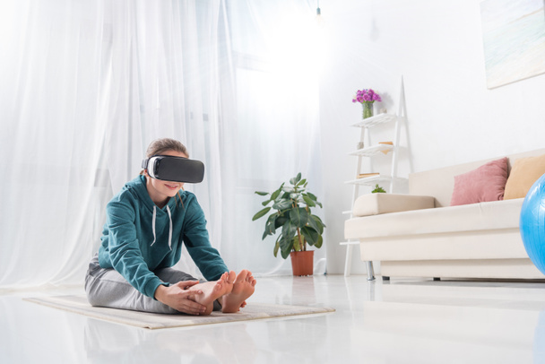 girl stretching with virtual reality headset on yoga mat at home - Fotografie, Obrázek