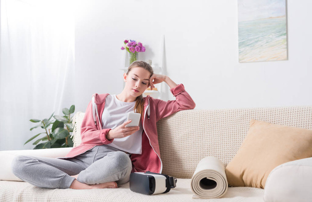 girl using smartphone on sofa at home - Foto, imagen