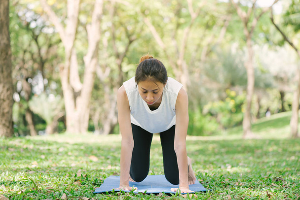 Joven mujer asiática yoga al aire libre mantener la calma y medita mientras practica yoga para explorar la paz interior. El yoga y la meditación tienen buenos beneficios para la salud. Yoga Deporte y estilo de vida saludable
. - Foto, Imagen