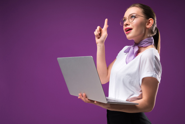 girl holding laptop and showing idea gesture isolated on purple - Fotó, kép
