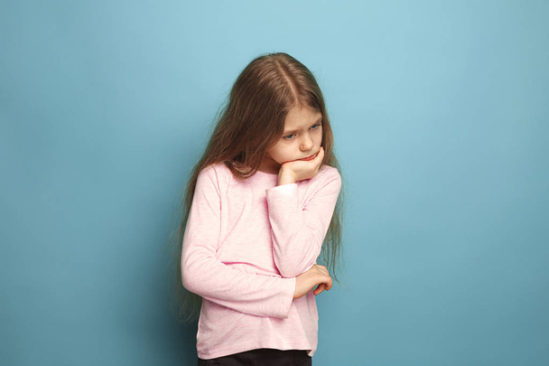 The thoughtful girl. Teen girl on a blue background. Facial expressions and people emotions concept - Foto, Bild