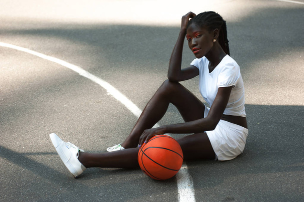 Beautiful young afro-american girl in white with orange basketball - Φωτογραφία, εικόνα