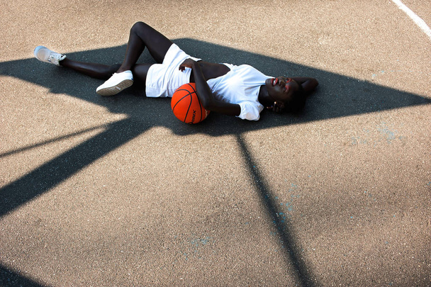 Dreamy afro-american model in white with basketball in shade - Foto, afbeelding